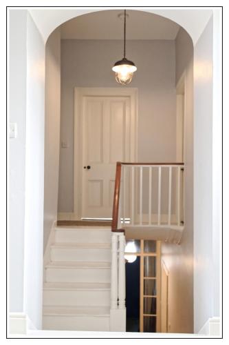 a hallway with white stairs and a white door at Harbour Bar Apartment in Greencastle