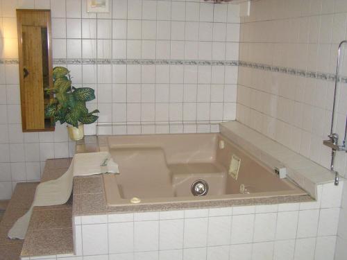 eine Badewanne in einem weiß gefliesten Bad mit einer Pflanze in der Unterkunft Fredrika Hotell Jakt&Fiskecamp in Fredrika