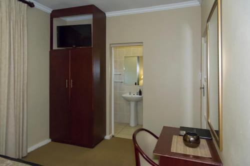 a room with a table and a bathroom with a sink at Bayswater Lodge in Bloemfontein