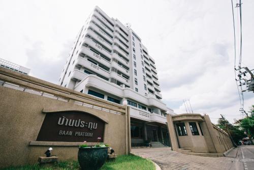 a tall white building with a sign in front of it at Baan Pratoom in Bangkok
