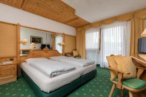 a hotel room with a large bed and a desk at Garni Criss in Colfosco