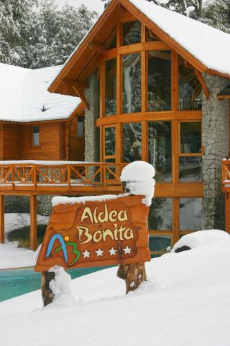 a sign in the snow in front of a log cabin at Aldea Bonita in Villa La Angostura