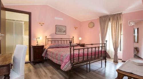 um quarto com uma cama com paredes cor-de-rosa e uma mesa em Villa Mereghetti em Corbetta
