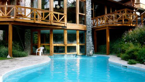 a house with a swimming pool in front of a building at Aldea Bonita in Villa La Angostura