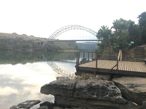 a bridge over a river with a bridge in the background at Villa Caylee Caribbean Estates - Ultra-Luxurious - Rimas Interiors Designs - Private Beachfront Escape - Premium serviced for 8 Guests in Port Edward