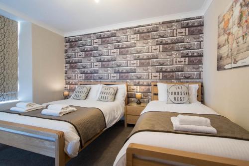 a bedroom with two beds and a brick wall at Thornbank House Offering Breakfast and with the use of Free Local Health Club in Windermere