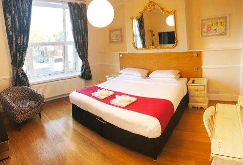 a hotel room with a bed, chair, lamp and window at Gidea Park Hotel in Romford