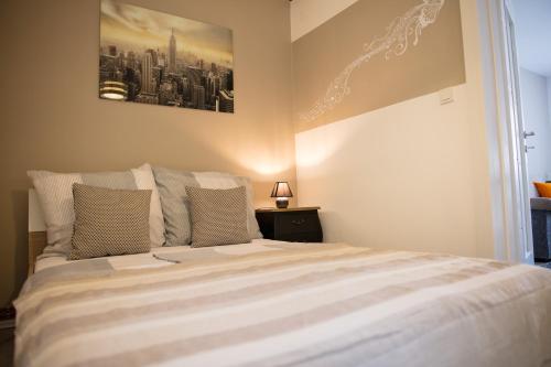 a bedroom with a large white bed with a picture on the wall at Apartment Impression in Osijek