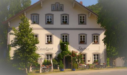 a white building with tables and chairs in front of it at Landgut Stetter in Schöllnach