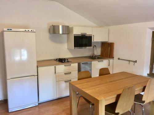 a kitchen with a wooden table and a white refrigerator at Riva San Vito 2 in Grado