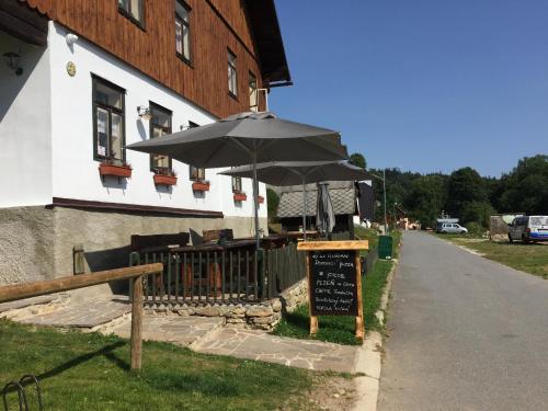 a cafe with an umbrella in front of a building at Wellness Hotel Florián České Žleby in Stožec