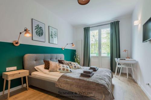 a bedroom with a bed and a green accent wall at Family Luxury Green Apartment 1-6, 2 sypialnie i studio, 52 m2 in Gdańsk