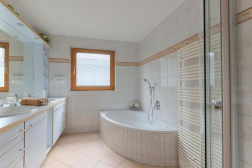 a bathroom with a tub and two sinks and a shower at AKTIV Apartments in Leutasch