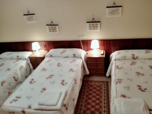 two beds in a small room with red walls at Hostal Mayo in O Barco de Valdeorras