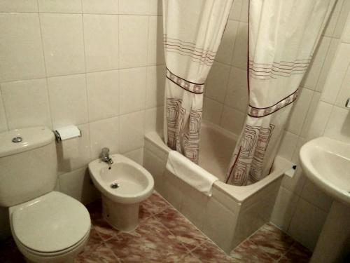 a white bathroom with a toilet and a sink at Hostal Mayo in O Barco de Valdeorras