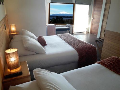 a hotel room with two beds with a view of a mountain at Dein Haus Hotel y Departamentos in Puerto Varas