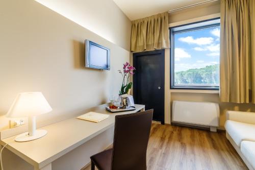 a hotel room with a desk with a couch and a window at Hotel Country Club in Capannori