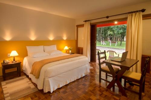 a bedroom with a bed and a desk with a laptop at Hotel Jardim Europa in Ijuí