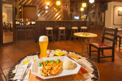 a table with a plate of food and a glass of beer at Hotel Jardim Europa in Ijuí