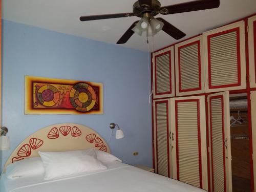 a bedroom with a bed and a ceiling fan at Las Palmeras RIKI R in Boca Chica