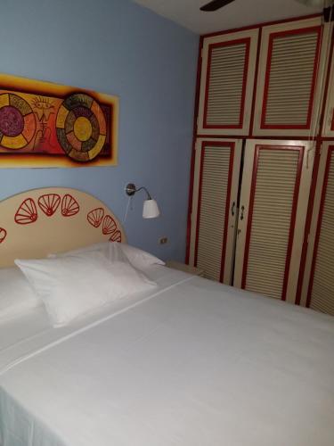 a bedroom with a large white bed and a window at Las Palmeras RIKI R in Boca Chica