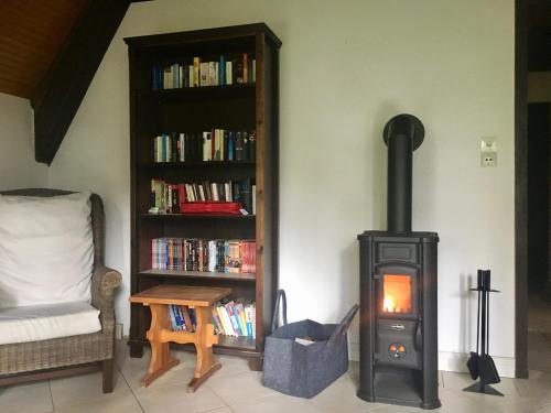 a wood stove in a living room with a book shelf at Reetdach-Ferienhaus in Quilitz in Rankwitz