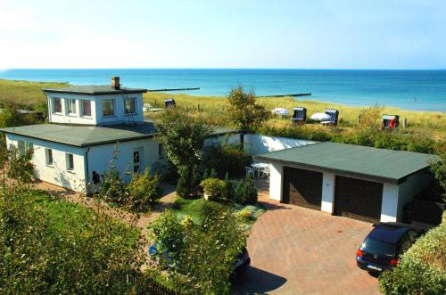 a house with a car parked in front of the ocean at Haus Windhook in Dierhagen