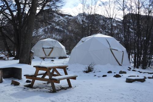 a picnic table and two tents in the snow at Camping Rio de las Vueltas in El Chalten