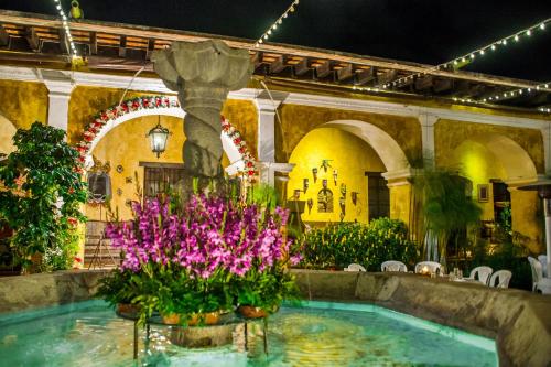 una piscina en un edificio con flores y una fuente en Hotel Convento Santa Catalina by AHS, en Antigua Guatemala