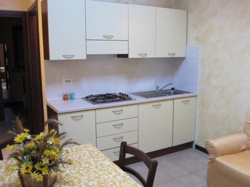 cocina con armarios blancos, fregadero y mesa en Agriturismo Tenuta Santa Maria en Notaresco