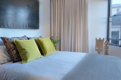 a bedroom with a large bed with yellow pillows at The KC Elizabeth Bay in Sydney