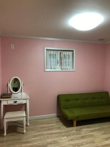 a living room with a green couch and a mirror at Namhae Frankfurt Pension in Namhae