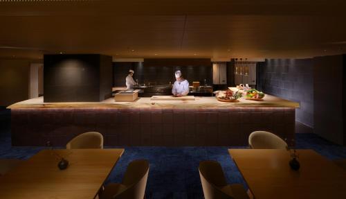 two people standing in a kitchen with a counter at Toba International Hotel in Toba