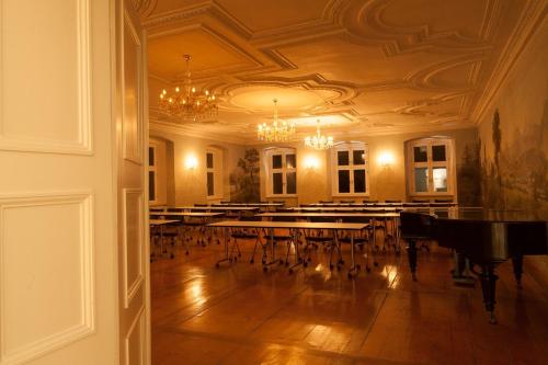 a room with a piano and tables and chairs at Hotel Kloster Holzen in Allmannshofen