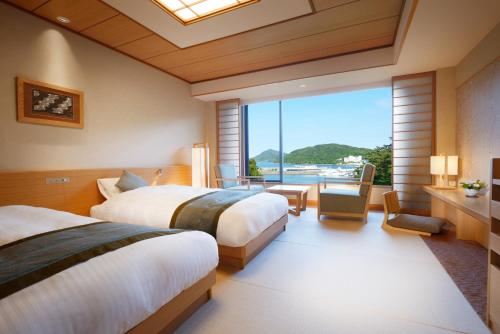 Habitación de hotel con 2 camas y ventana grande. en Toba International Hotel Shiojitei en Toba