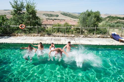 a group of people jumping in a swimming pool at Podere Spedalone in Pienza
