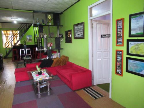 a living room with a red couch and green walls at Green Savannah Homestay Syariah in Dieng