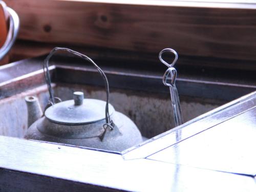 a metal tea kettle sitting on top of a stove at Uminchuno Yado in Nago