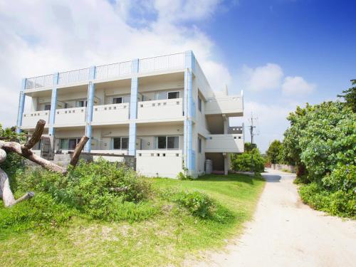 a white building on the side of a dirt road at Uminchuno Yado in Nago