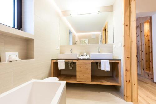 a bathroom with two sinks and a bath tub at Hotel Eden in Solda