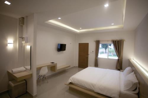 a bedroom with a bed and a desk and a window at West View Villa in Kanchanaburi
