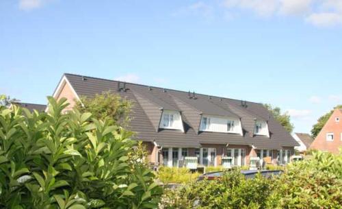a house with a black roof and some trees at To Eek in Tinnum