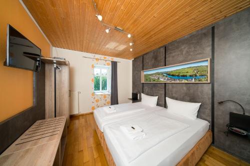 ein großes weißes Bett in einem Zimmer mit einem TV in der Unterkunft Hotel Moselsteig in Osann-Monzel