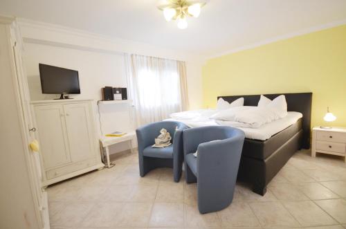 a bedroom with a bed and a chair and a tv at Ostseehaus Dreesen in Timmendorfer Strand