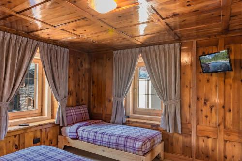 a bedroom with a bed and two windows at Bait da Menego in Livigno