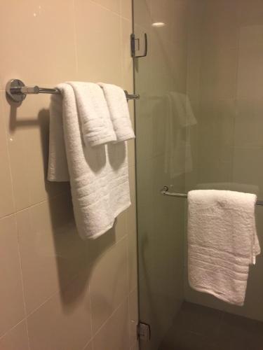 a bathroom with white towels on a glass shower door at Eton Baypark in Manila