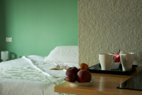 a tray with coffee cups and fruit on a bed at Cascina delle Mele in Vittuone