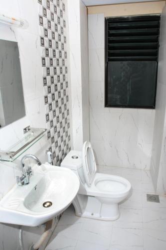 a white bathroom with a toilet and a sink at Thamel Backpackers Home in Kathmandu