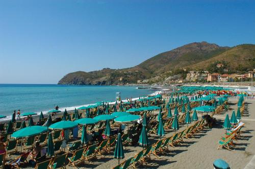 レヴァントにあるPino - Baroloの多くの椅子とパラソルと海を備えたビーチ