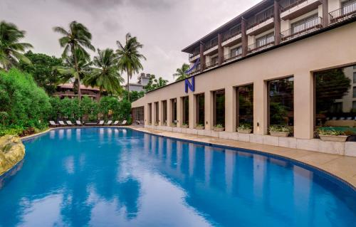 a swimming pool in front of a building at Novotel Goa Candolim in Candolim